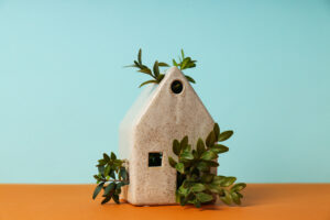 Maquette de maison en céramique entourée de jeunes pousses vertes