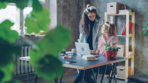 Deux femmes échangent autour d'un ordinateur portable dans un bureau lumineux